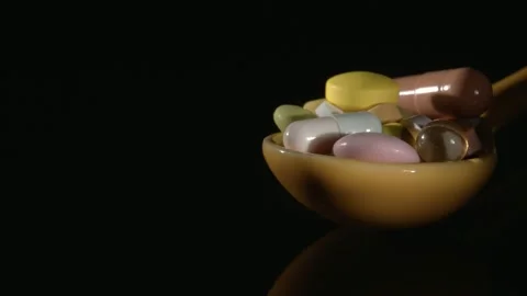 Medications in a close-up spoon on a black background. Видео 146728385