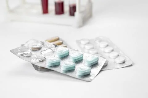 Medications in packages and blood samples in test tubes in the background. on Stock Photos