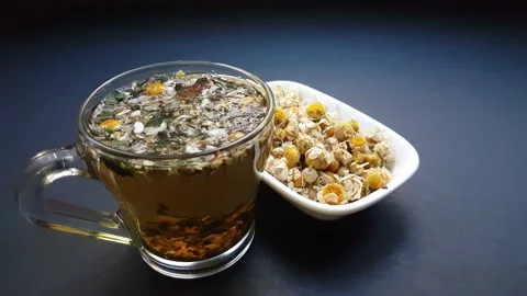 Medicinal aromatic herb chamomile tea in white bowl on black background 스톡 동영상 147227145