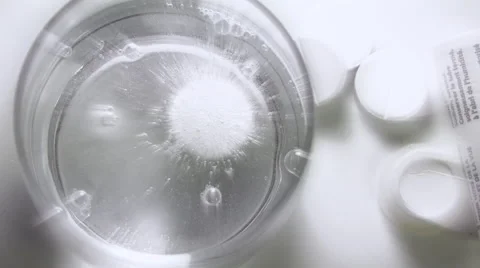 Medicine, aspirin tablet dissolving in water on a white background - high angle Video stock 59557176