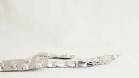Medicine blister pack falling and piling up on white background Stock Footage 228660875