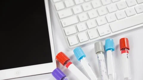 Medicine bottles for samples next to computer tablet and computer keyboard in 스톡 사진