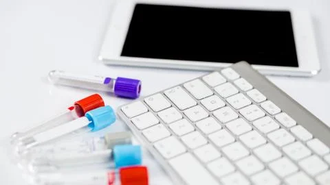 Medicine bottles for samples next to computer tablet and computer keyboard in Stock Photos