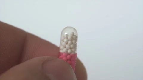 Medicine, capsule with pellets in man's fingers.Close up Stock Footage 127621053
