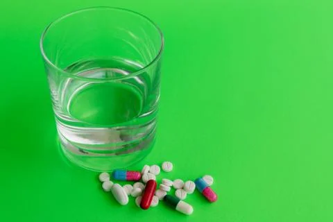 Medicine capsules and glass of water Stock Photos