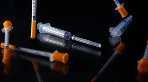Medicine concept, syringes falling down on reflective sirface, slow motion. Vídeo Stock 54454363