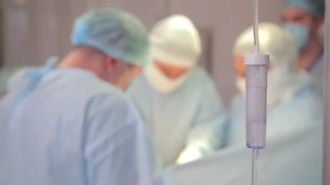 Medicine drips one drop at a time, in the foreground. doctors out of focus Video stock 135306825