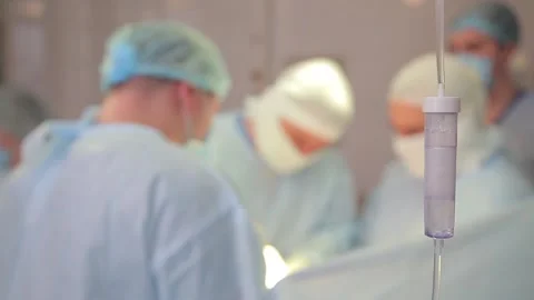 Medicine drips one drop at a time, in the foreground. doctors out of focus Video stock 135306862