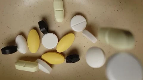 Medicine tablets falling into a ceramic bowl in slow motion Stock Footage 135409466