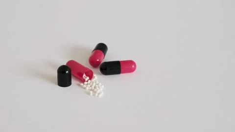 Medicines in black-red capsules. One capsule is opened and the substance that fi Stock Footage 234524030