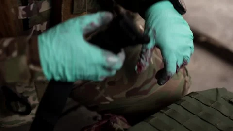 Medic's bloody hands preparing tactical tourniquet Stock Footage 331425975