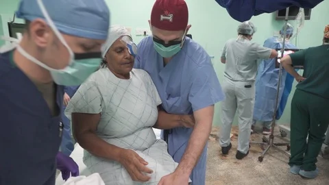 Medics help patient climb down from bed after cataract removal surgery Vídeo Stock 107977598