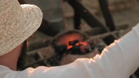 Medieval artisan blows fire under the iron bar Stock Footage 79998245