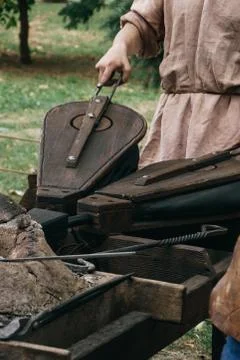 Medieval blacksmith using bellows to kindle fire Stock Photos