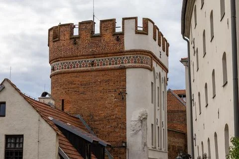 Medieval brick gate tower from 1432 stands beside historic buildings in Torun. 스톡 사진