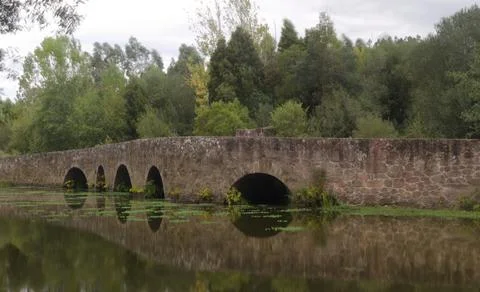 Medieval bridge built in mirror stone on river Stock Photos