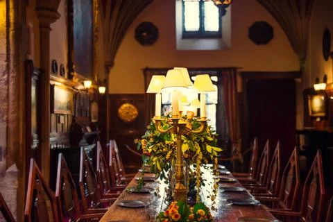 Medieval british castle interior dining table with plates, flowers and lamps. Stock Photos