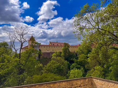 A medieval castle complex with stone towers stands behind a lush green park Stock Photos
