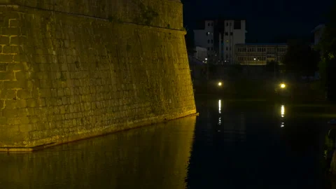 Medieval castle moat with golden light reflections at night Vídeos de archivo 334817018