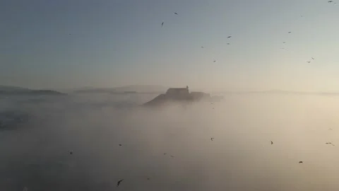Medieval castle on top of a hill surrounded by mist and flying birds Stock Footage 212389819