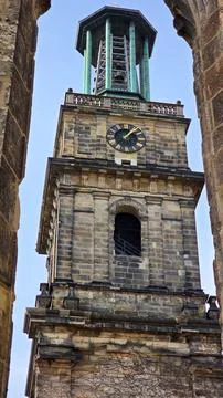 A medieval clock tower with a clock atop, standing tall in the city skyline Stock Photos