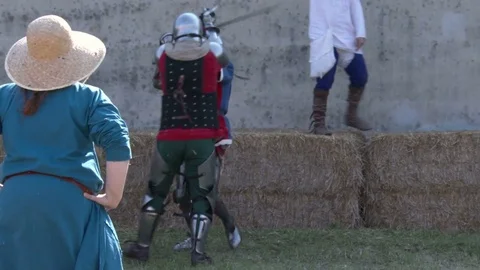 Medieval combat. Two men dressing metal armor fight a sword-fired duel. Slowmo.  Stock Footage 76250342