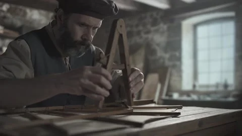 A medieval craftsman checking an ornithopter wing with a divider tool 스톡 동영상 340079534