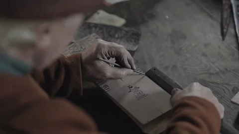 Medieval craftsman hand paints pattern onto textile printing block #4 Stock Footage 320250859