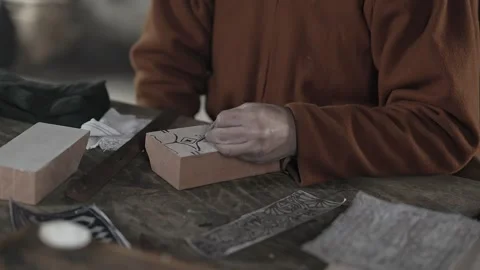Medieval craftsman hand paints pattern onto textile printing block #2 Stock Footage 320251048
