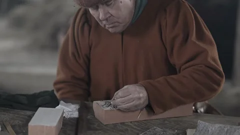 Medieval craftsman hand paints pattern onto textile printing block #1 Stock Footage 320251522