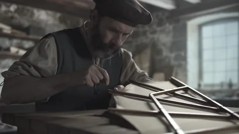 A medieval inventor wrapping linen thread around an ornithopter wing rib end 库存影片 340502586