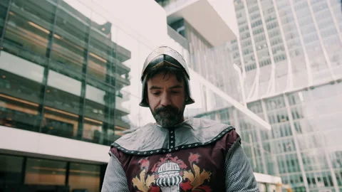 Medieval knight expressing surprise while surrounded by modern skyscrapers Stock Footage 130259052