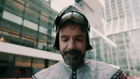 Medieval knight expressing surprise while surrounded by modern skyscrapers Stock Footage 130259349