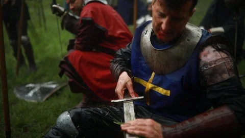 Medieval knight sits in armor and cleans his sword. Stock Footage 109490180