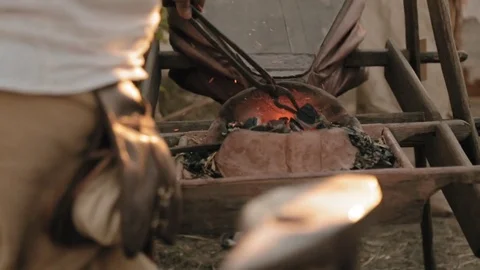 Medieval man blows the coals by blower Stock Footage 79997999