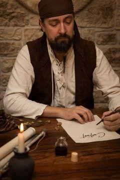 Medieval man sitting on a table and sign a contract Fotos Stock