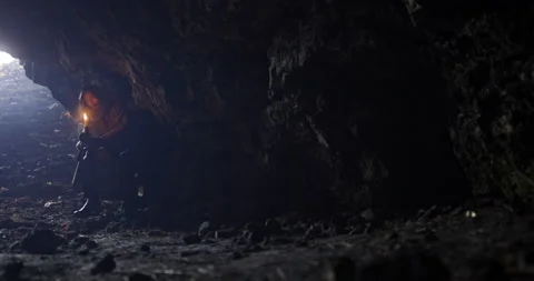 Medieval monk, or beggar, with a beard sits in a dark cave with a candle in his Stock Footage 171475839