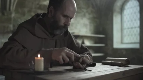 Medieval monk sharpening a penknife blade on a wet whetstone, medium shot Stock-Footage 337930163