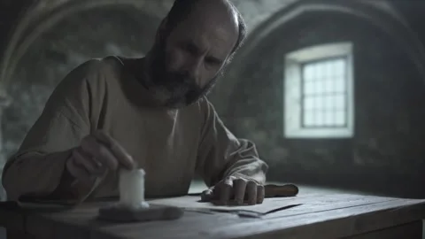 Medieval prisoner extinguishing a burning candle with his fingers inside a cell Stock Footage 340823643