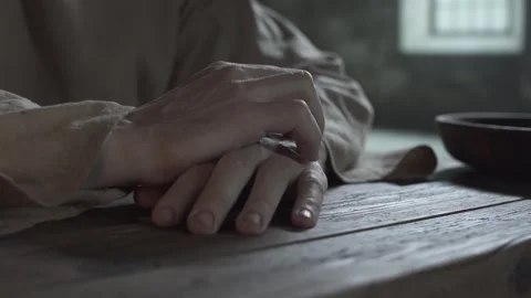 Medieval prisoner scratching his fingers at a table inside a jail cell Stock Footage 340502559