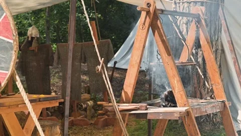 A medieval reenactment area with wooden frame structures and smoke rising from a Stock Footage 345031064