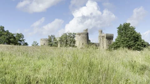 Medieval stone castle behind tall grass panning Stock Footage 336815647