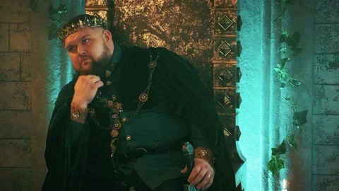 Medieval strong man king sits on old bronze throne, gold crown. Gothic castle Stock Footage 135565919