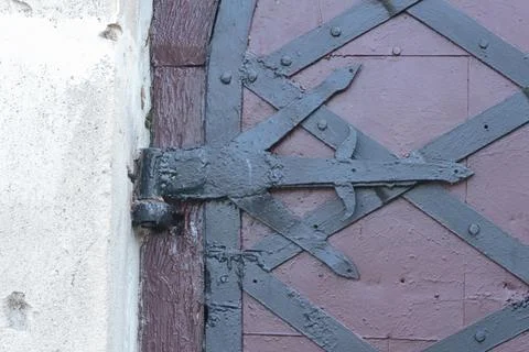 Medieval style black iron strap hinge on old painted wooden door close up Stock Photos