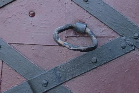 Medieval style black iron strap hinge on old painted wooden door close up Stock Photos