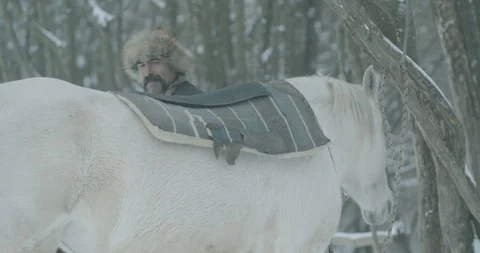 Medieval warrior puts a saddle on a white horse (S-log2) Stock Footage 100072988