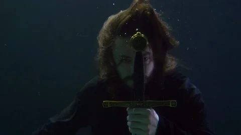 A medieval warrior with a sword under water waits for an attack on the enemy Vidéo 219541653
