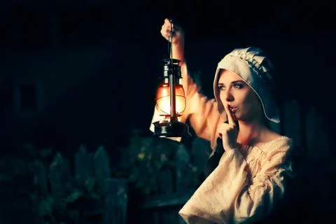 Medieval Woman with the Finger on the Lips Holding a Lamp Stock Photos