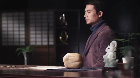 Meditating Asian man stroking jade stone in slow motion Stock Footage 30477498