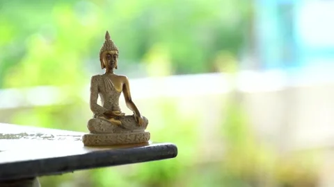 Meditating buddha with green &amp; rain background. Buddha bronze idol in a mindf Stock Footage 136952078